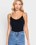 Woman wearing a black bodysuit and blue jeans against a white background