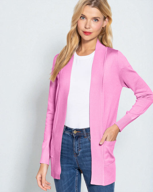 Woman wearing a pink cardigan over a white shirt and blue jeans on a light gray background