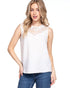 Woman wearing a white sleeveless top with lace details and blue jeans on a white background