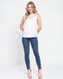 Woman wearing a white sleeveless top with lace details and blue jeans on a white background