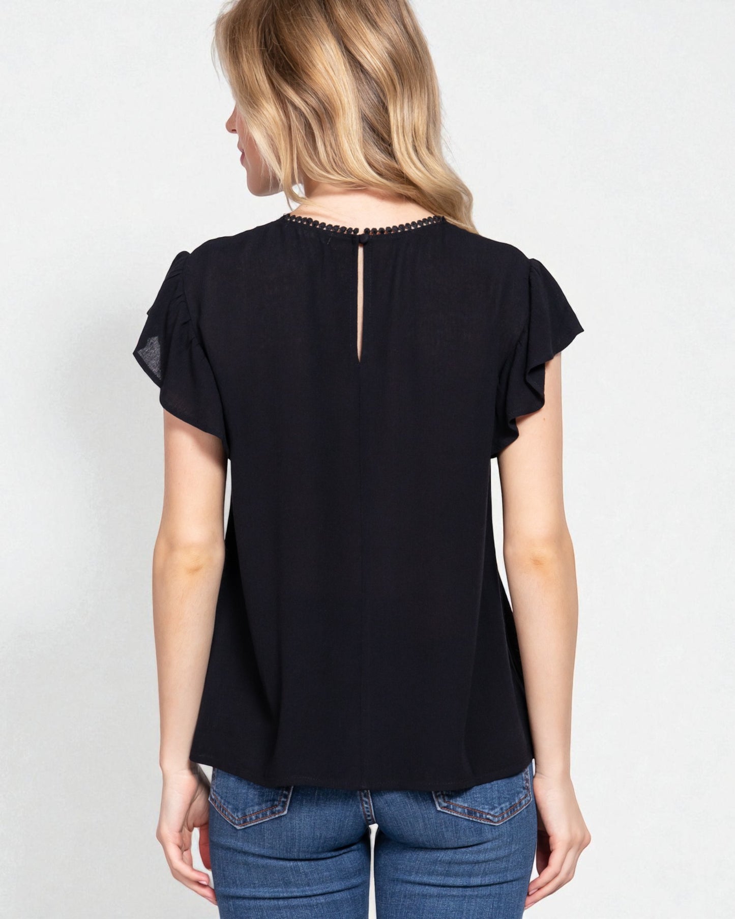 Woman wearing a black blouse with ruffled sleeves on a white background