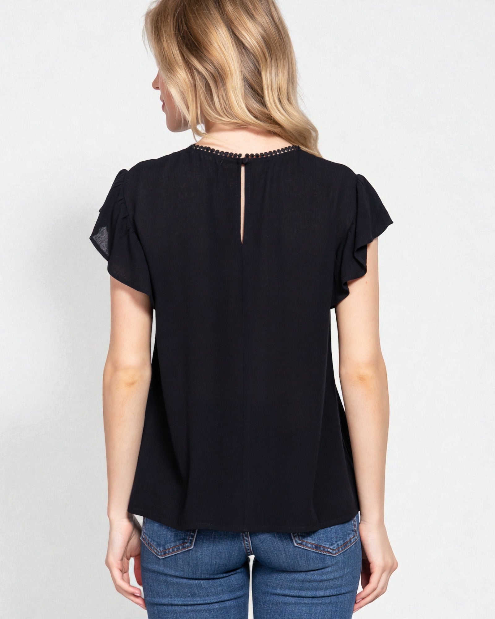 Woman wearing a black blouse with ruffled sleeves on a white background