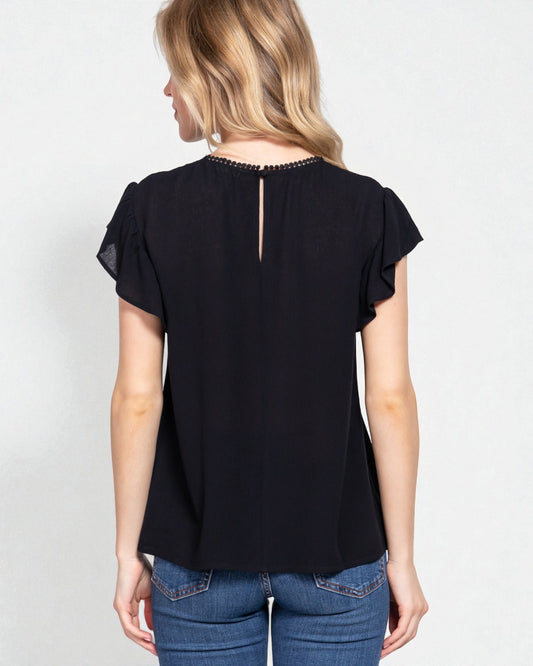 Woman wearing a black blouse with ruffled sleeves on a white background