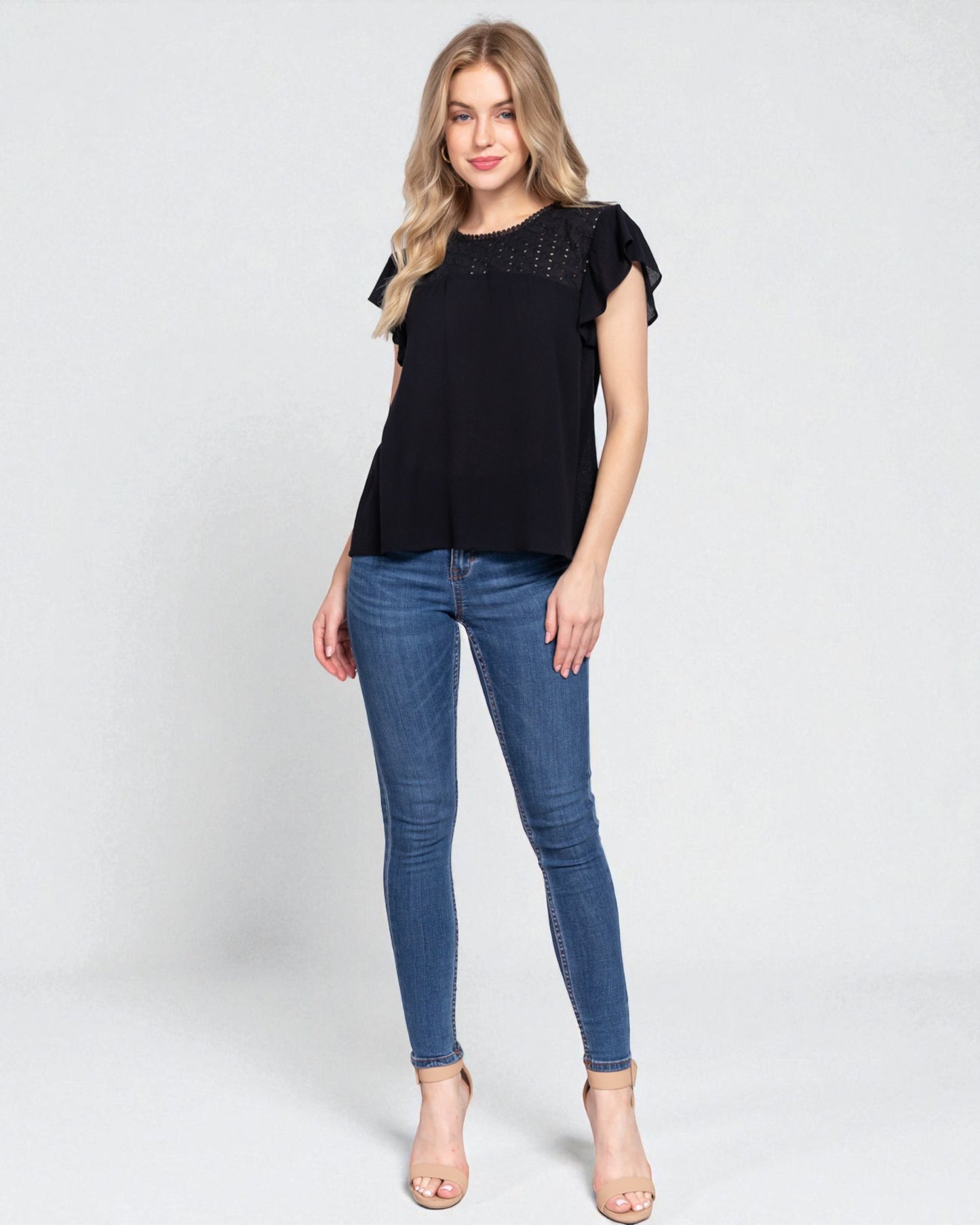 Woman wearing a black top and blue jeans on a white background