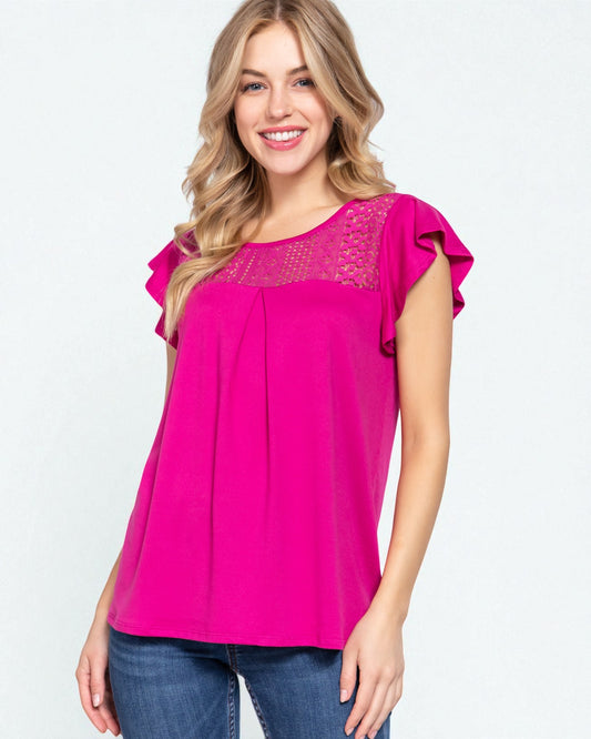 Woman wearing a bright pink blouse with lace details on a white background