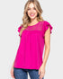 Woman wearing a bright pink blouse with lace details on a white background