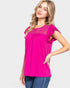 Woman wearing a bright pink top with lace details on a white background
