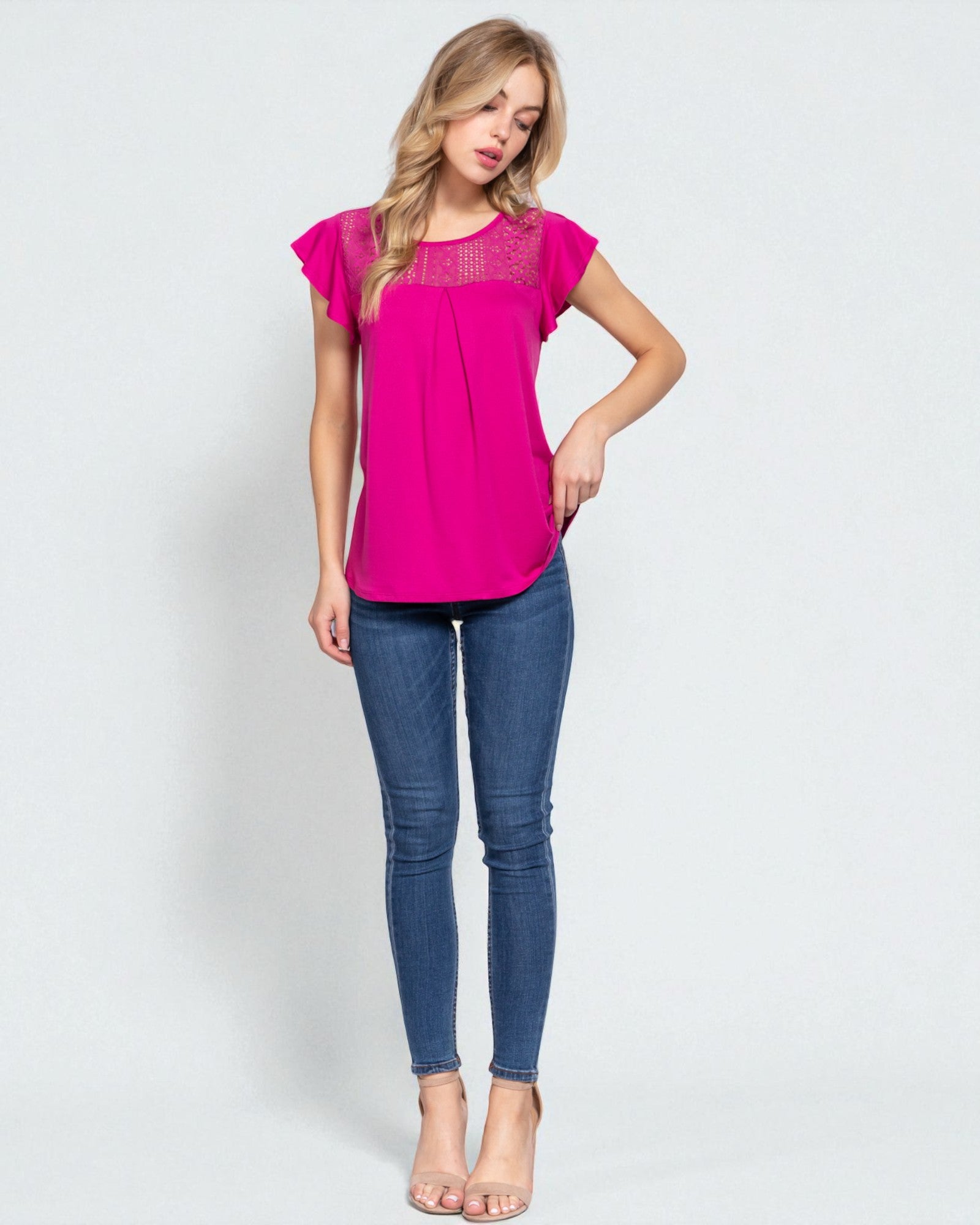 Woman wearing a pink top and blue jeans on a white background