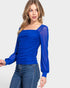 Woman wearing a blue top with long sleeves on a white background
