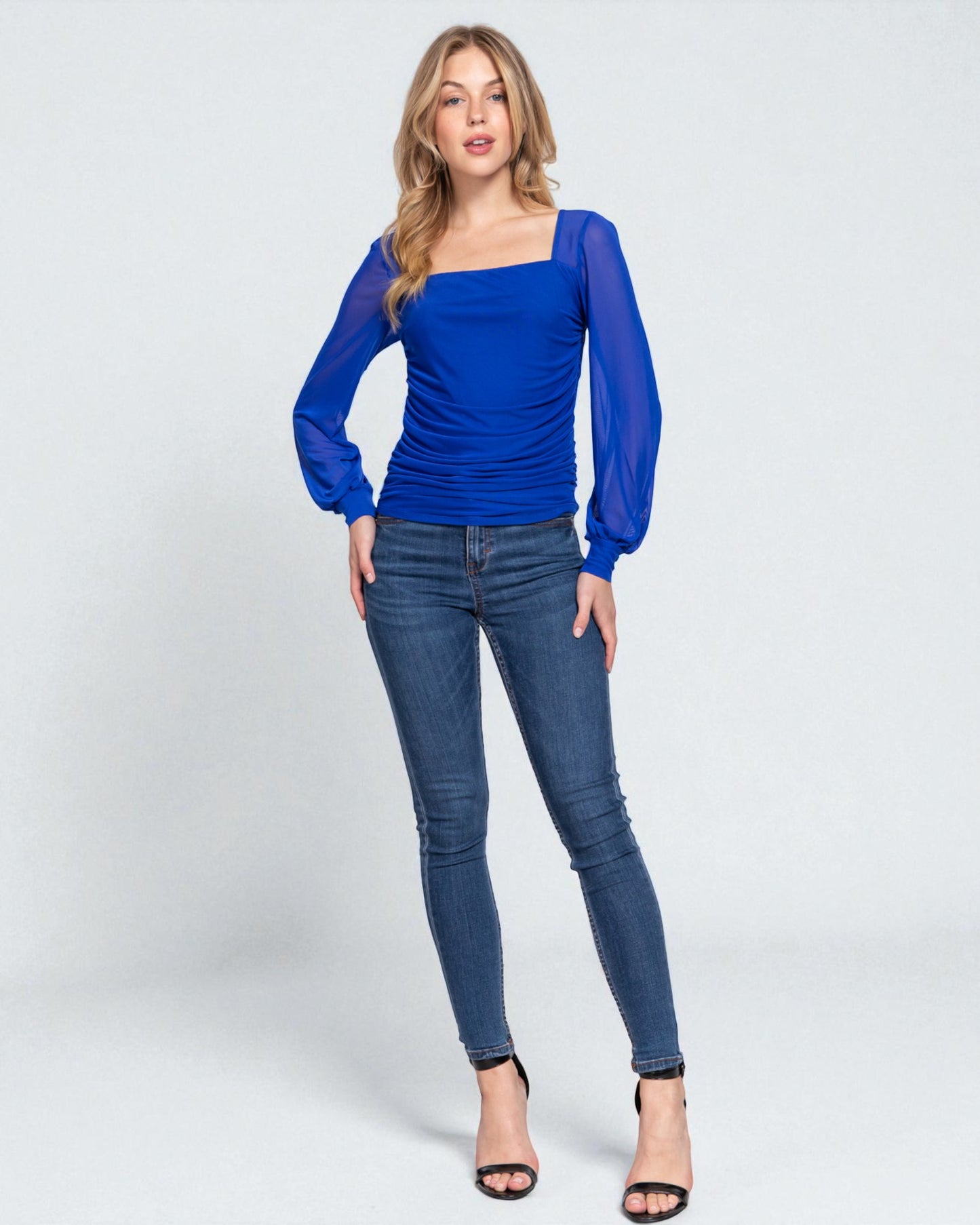 Woman wearing a blue top and jeans on a white background