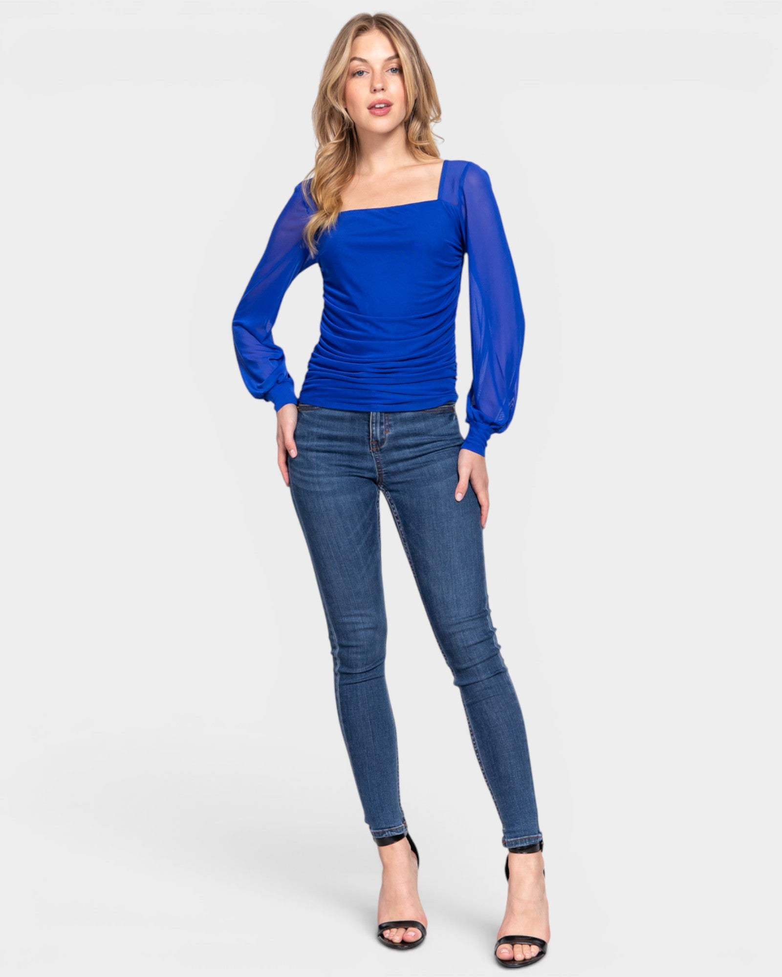 Woman wearing a blue top and jeans on a white background