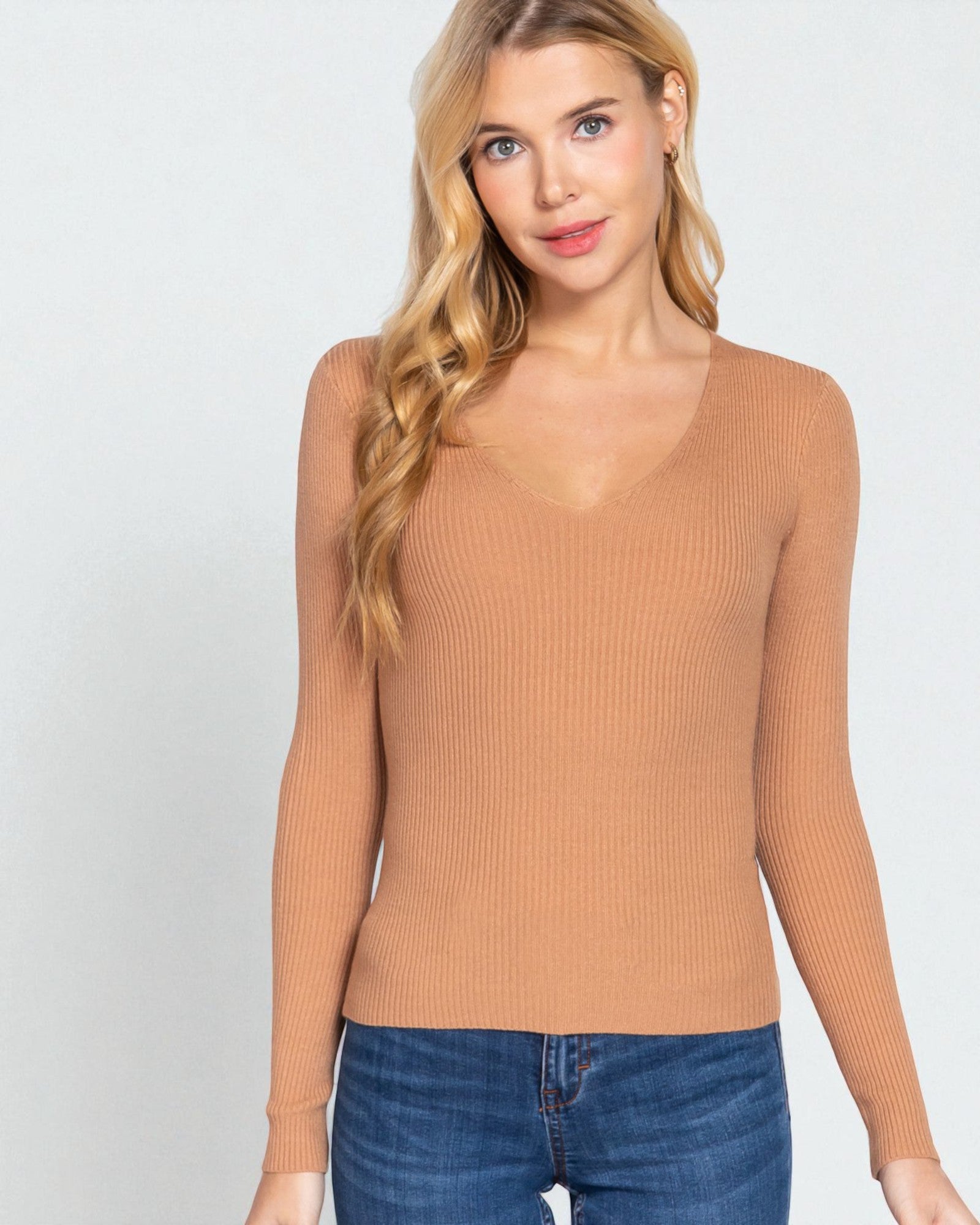 Woman wearing a tan ribbed long-sleeve top against a white background