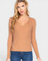 Woman wearing a tan ribbed tank top against a white background