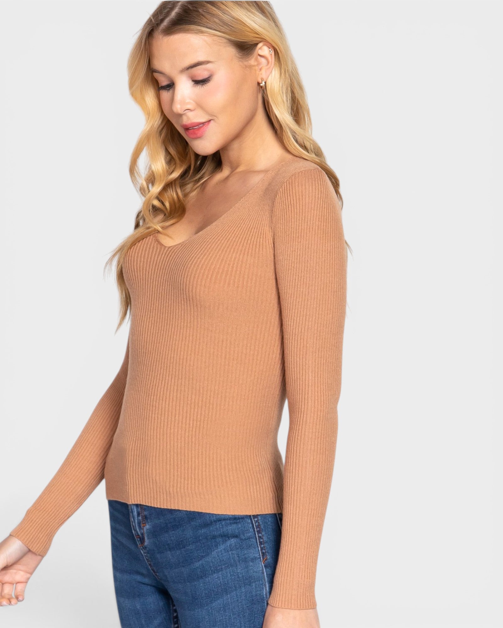 Woman wearing a brown sweater and blue jeans on a white background