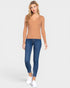 Woman wearing a tan sleeveless top and blue jeans on a white background