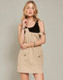 Woman wearing a beige apron over a black top on a plain background
