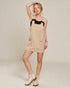 Woman wearing a beige dress with black accents on a plain background