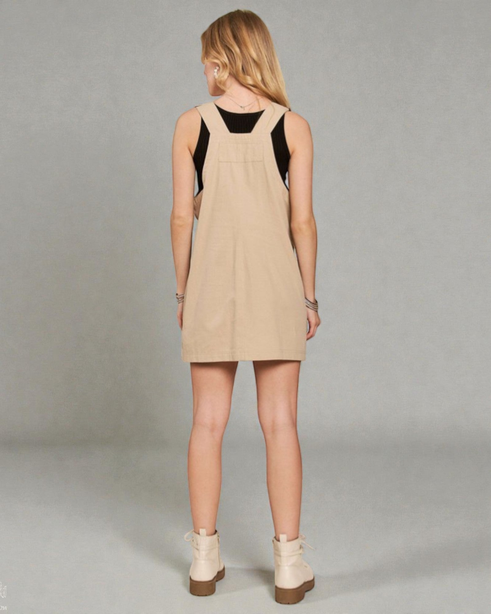 Woman wearing a beige dress with black top on a gray background