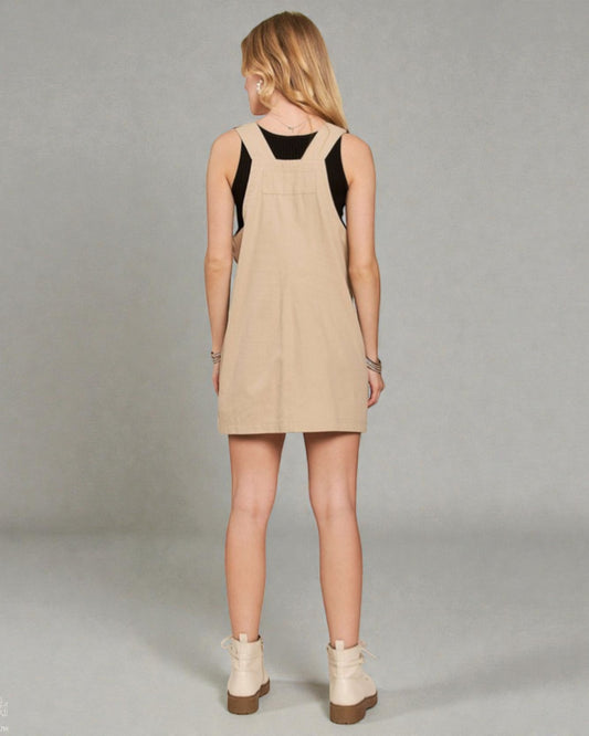 Woman wearing a beige dress with black top on a gray background