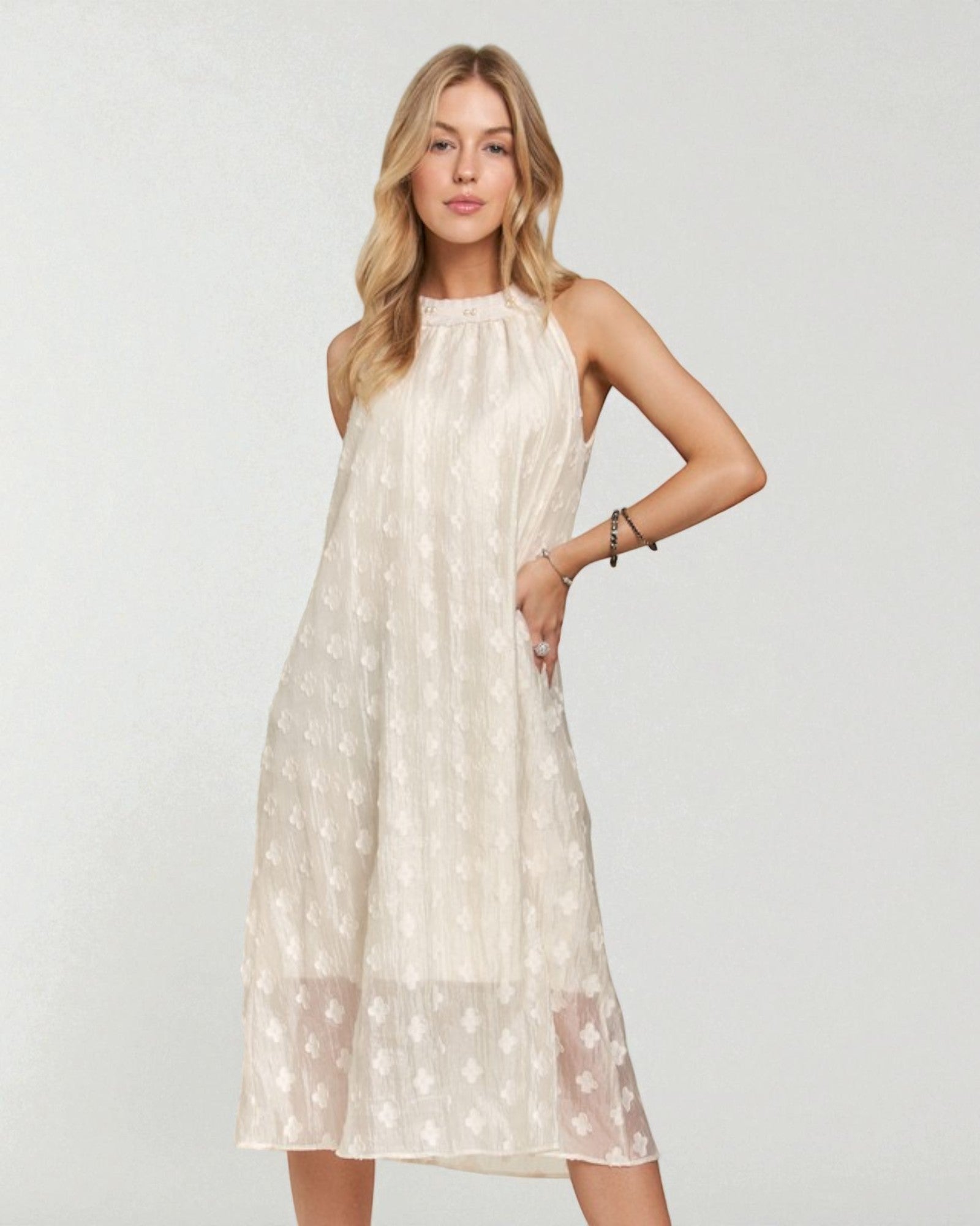 Woman wearing a beige sleeveless dress with floral patterns on a white background