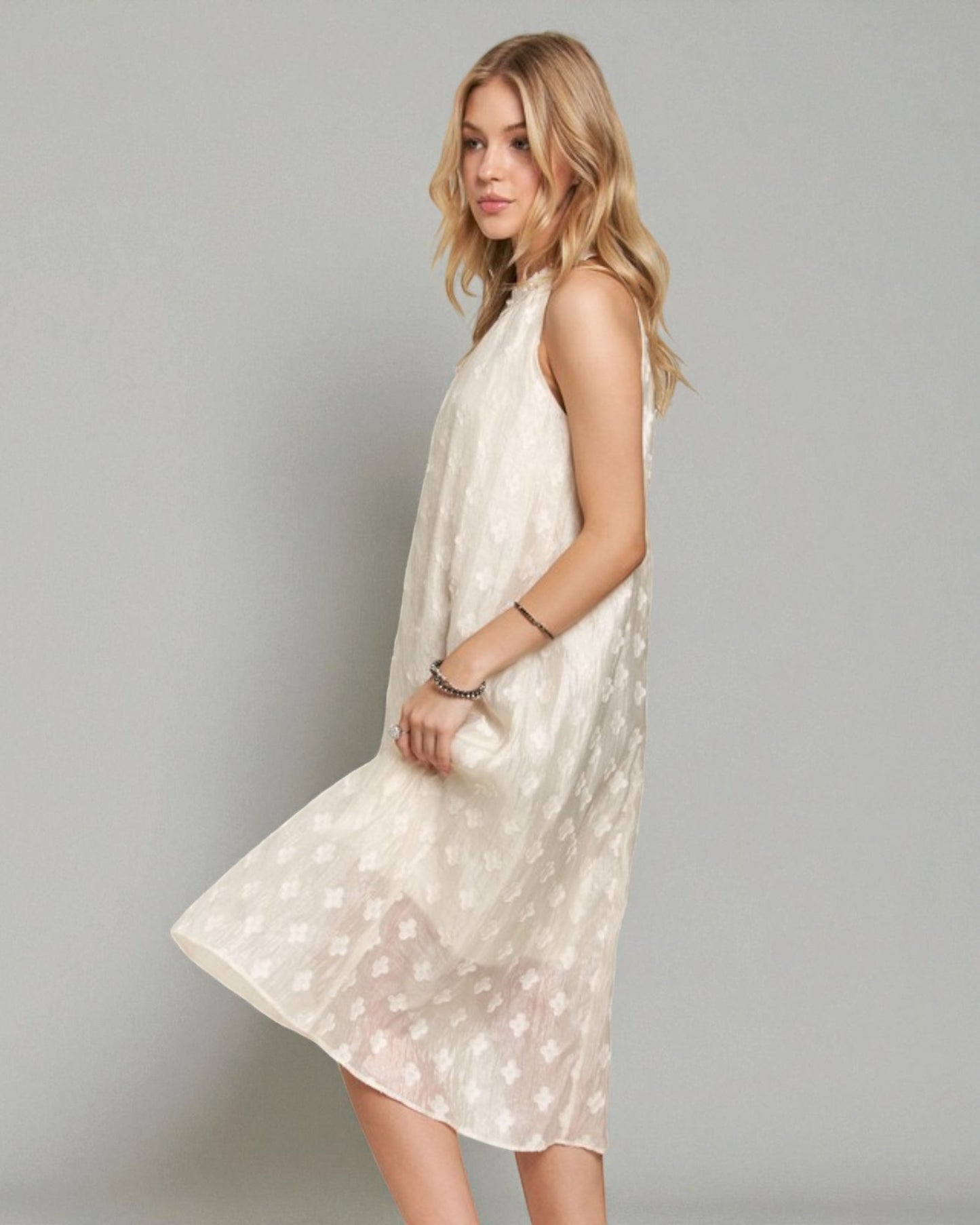 Woman wearing a white floral dress against a gray background