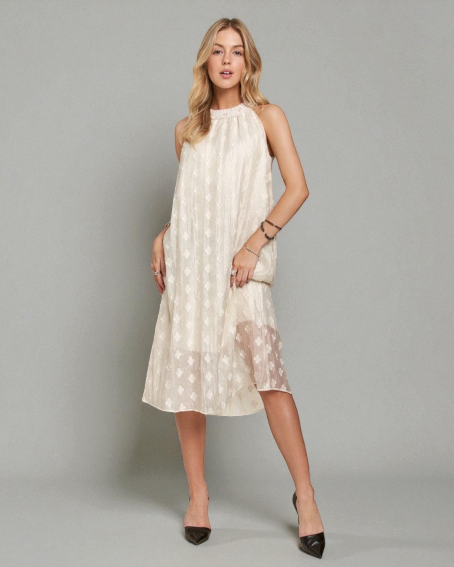 Woman wearing a white dress with a subtle pattern on a gray background