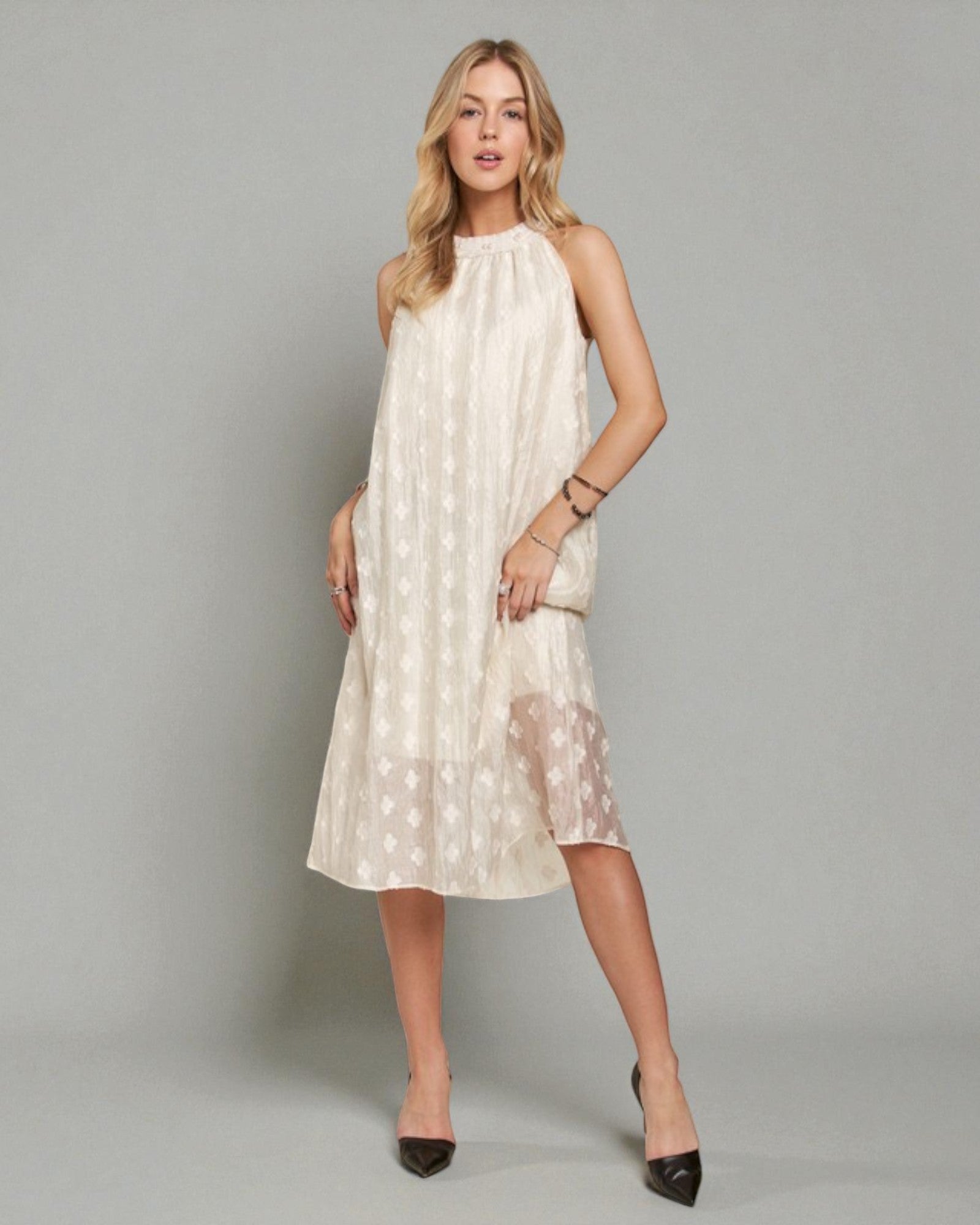 Woman wearing a white dress with a subtle pattern on a gray background