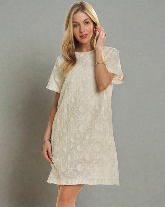 Woman wearing a beige lace dress against a gray background