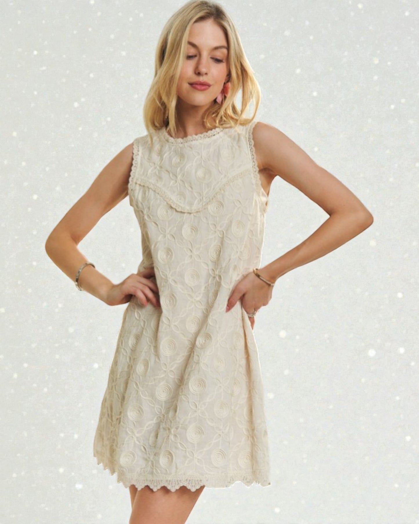 Woman wearing a beige lace dress against a light gray background