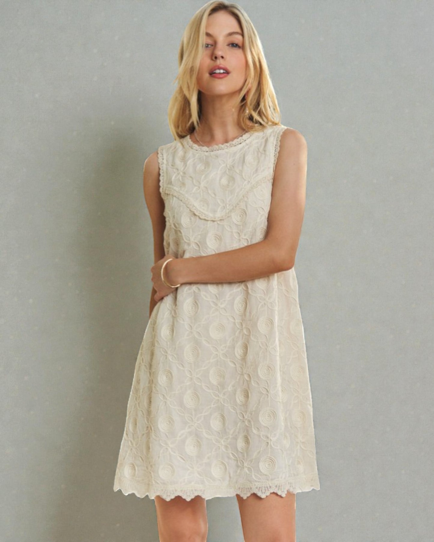 Woman wearing a white lace dress against a gray background