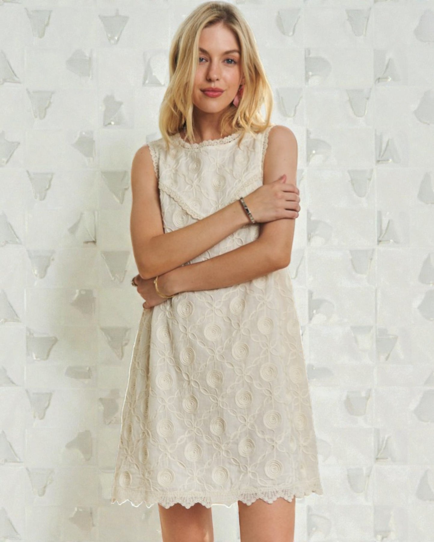 Woman wearing a white lace dress against a textured white background