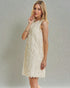 Woman wearing a beige lace dress against a gray background