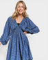 Woman wearing a blue patterned dress on a white background