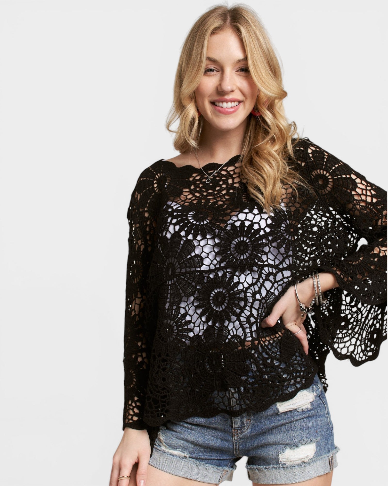 Woman wearing a black lace top with a plain background