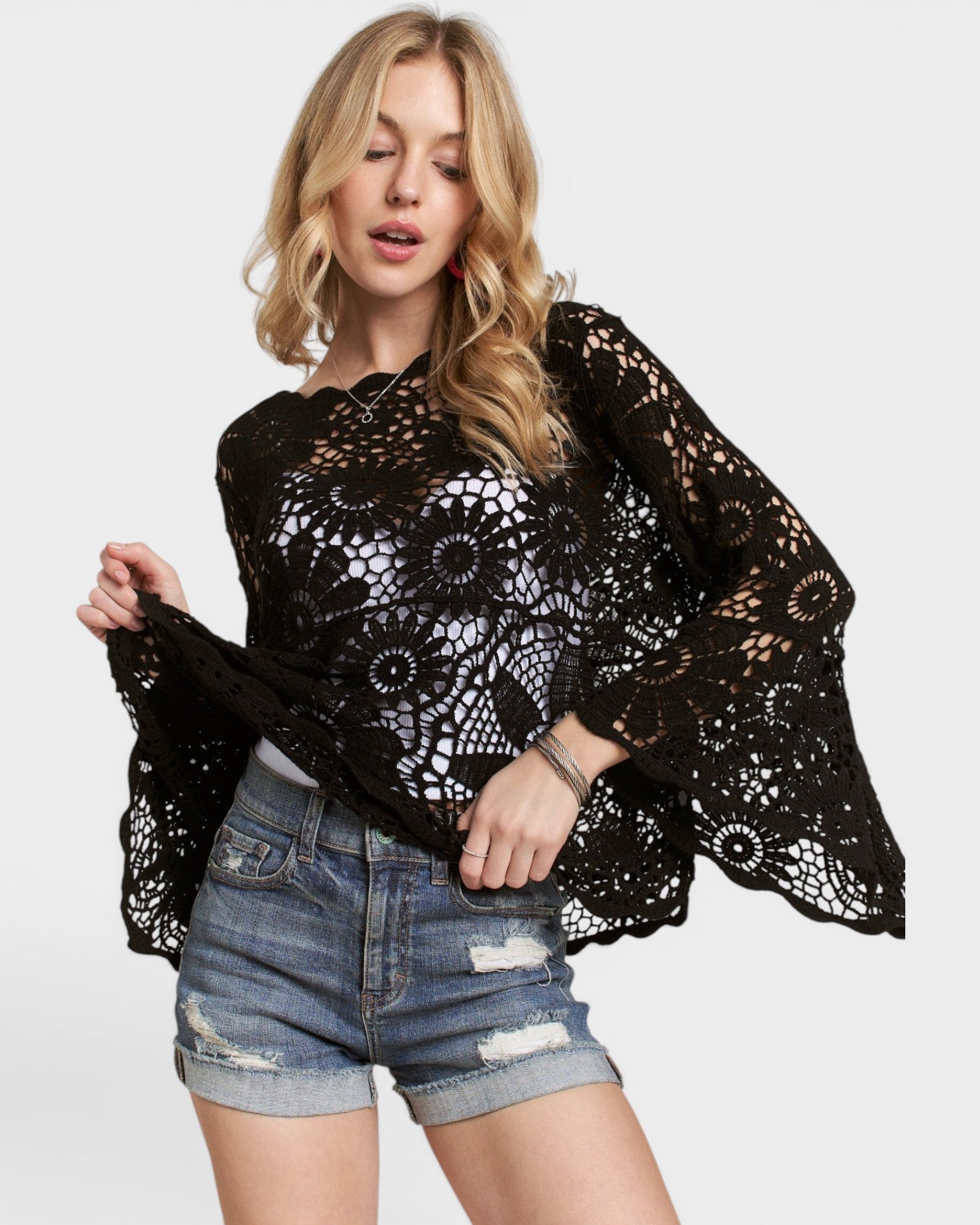 Woman wearing a black lace top and denim shorts on a white background