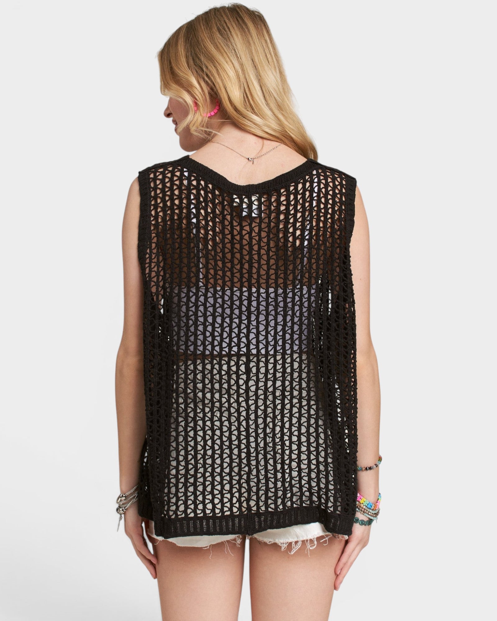 Woman wearing a black crochet sleeveless top on a white background
