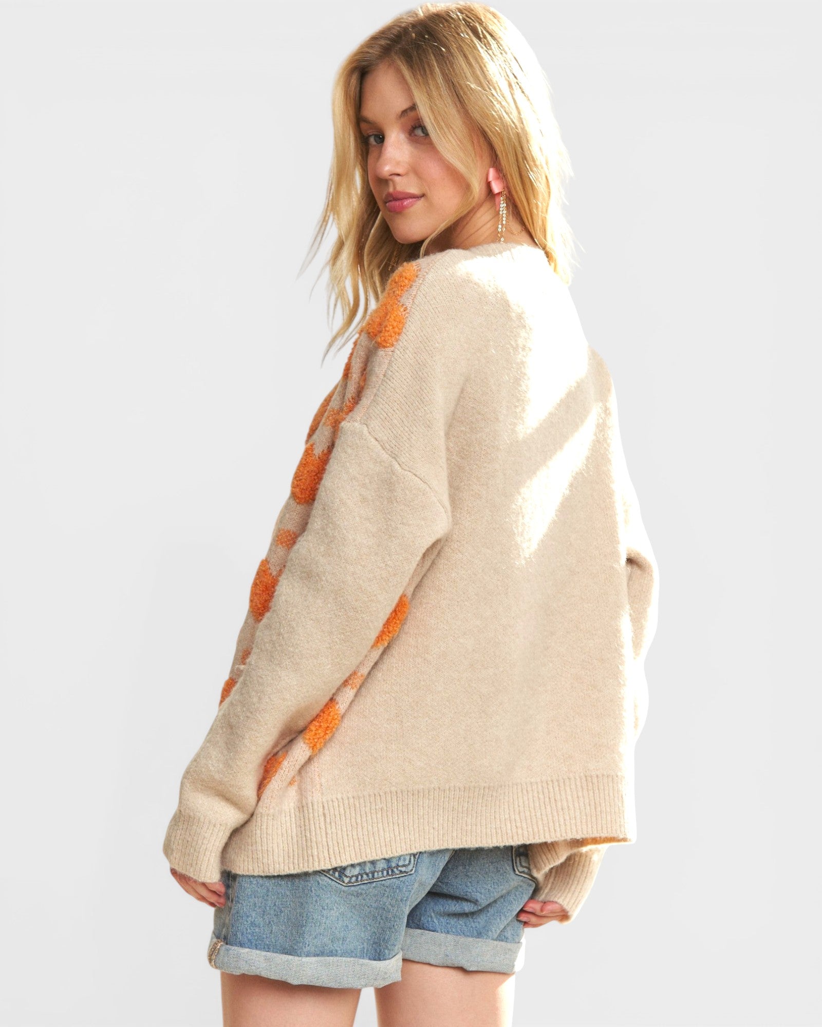 Woman wearing a beige sweater with orange pattern on a white background