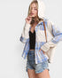 Woman wearing a plaid shirt over a hoodie with denim shorts on a white background