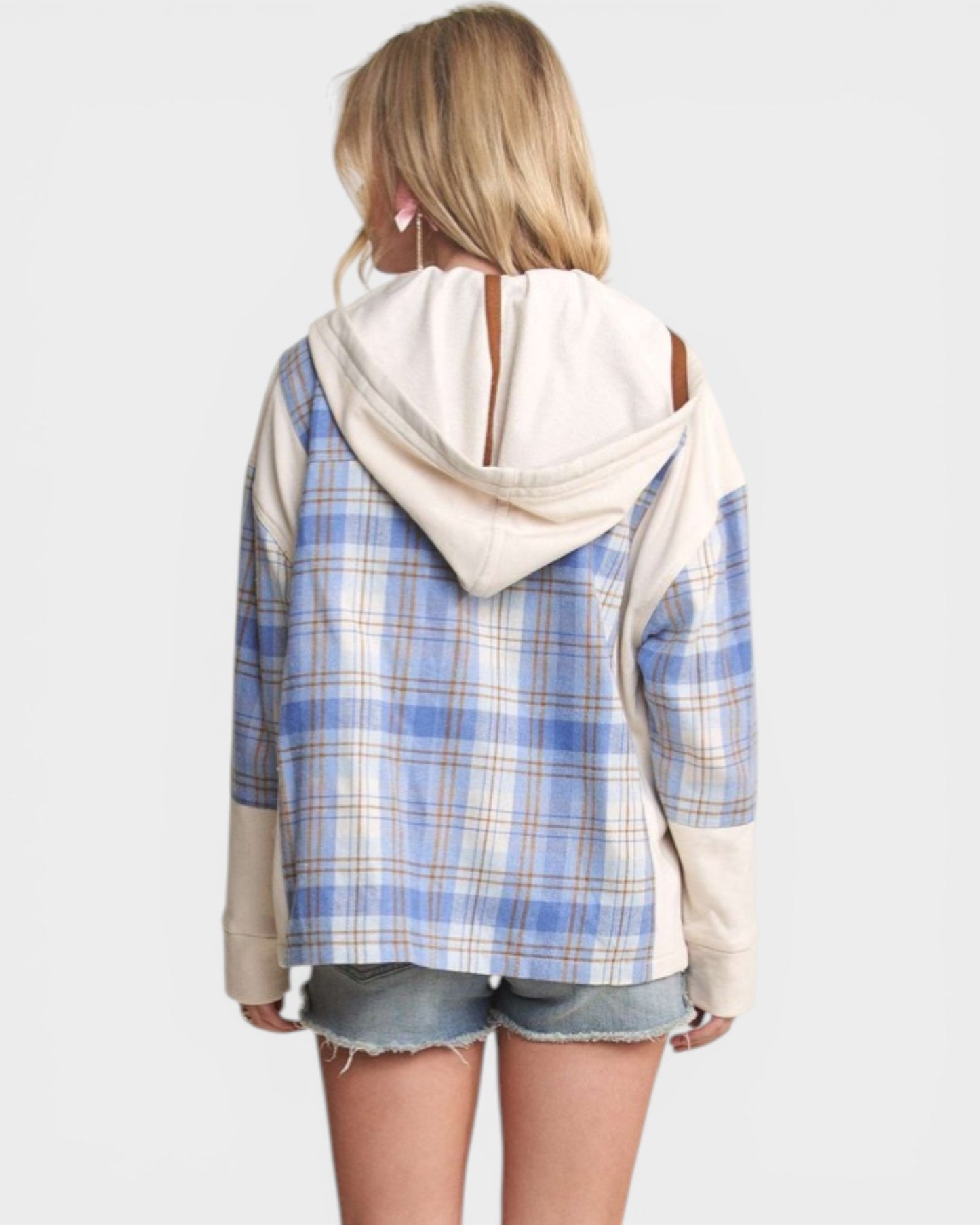 Person wearing a blue plaid shirt with a white hood over it on a plain background