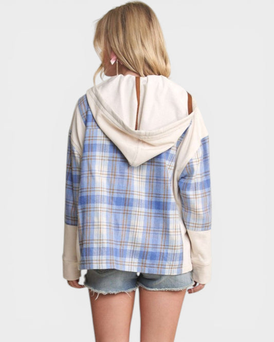 Person wearing a blue plaid shirt with a white hood over it on a plain background