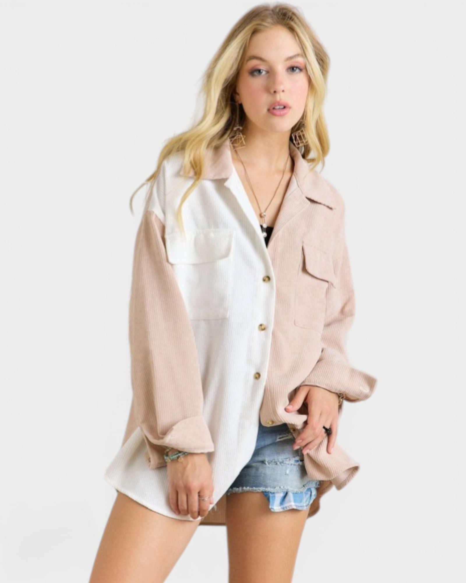 Woman wearing a light pink jacket over a white shirt with denim shorts on a white background