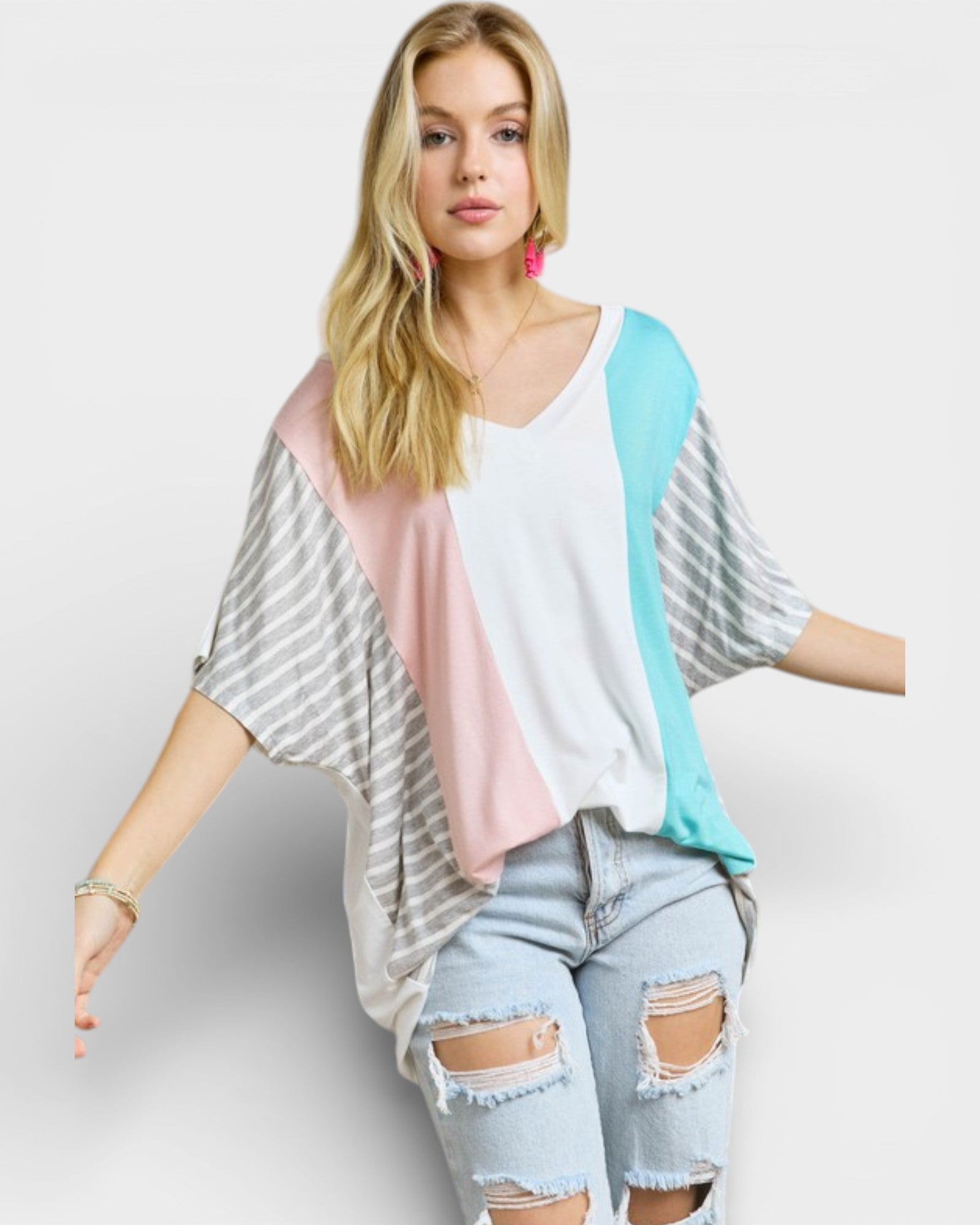 Woman wearing a colorful kimono-style top with ripped jeans on a white background