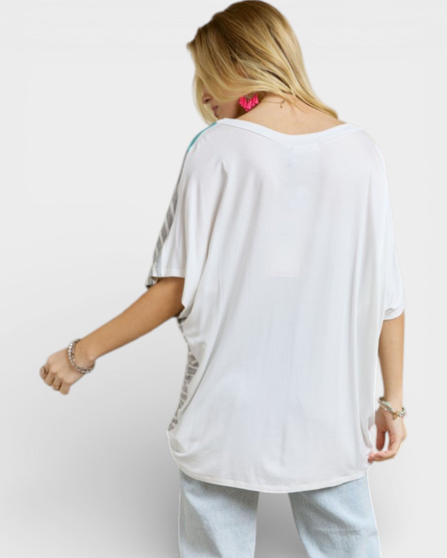 Woman wearing a white oversized t-shirt with a colorful design on a plain background