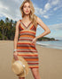 Woman in a patterned dress on a beach with palm trees and ocean in the background