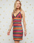 Woman wearing a colorful striped dress against a decorative gold bow background