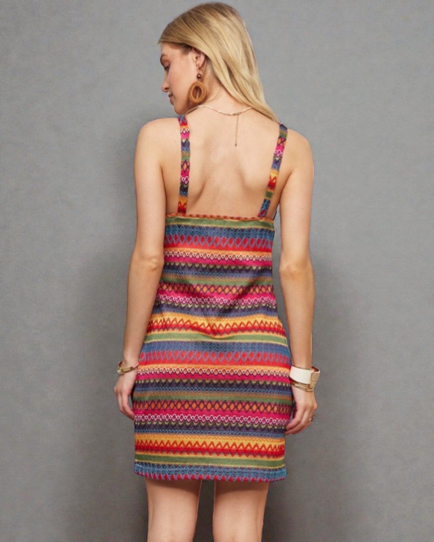 Woman wearing a colorful striped dress against a gray background