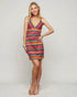 Woman wearing a colorful striped dress on a plain background