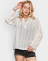 Woman wearing a white lace blouse with long sleeves on a plain background