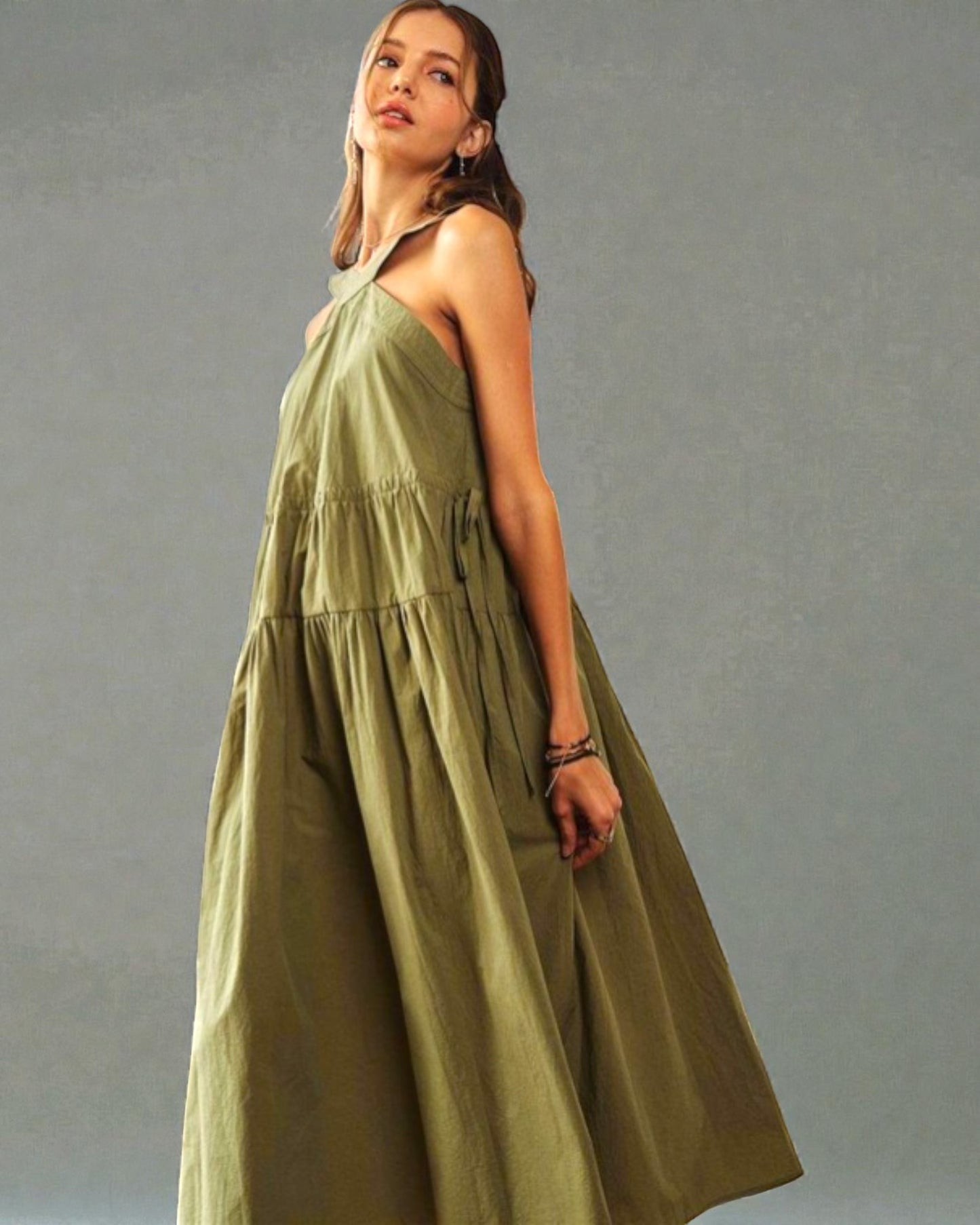 Woman wearing a long green dress against a gray background