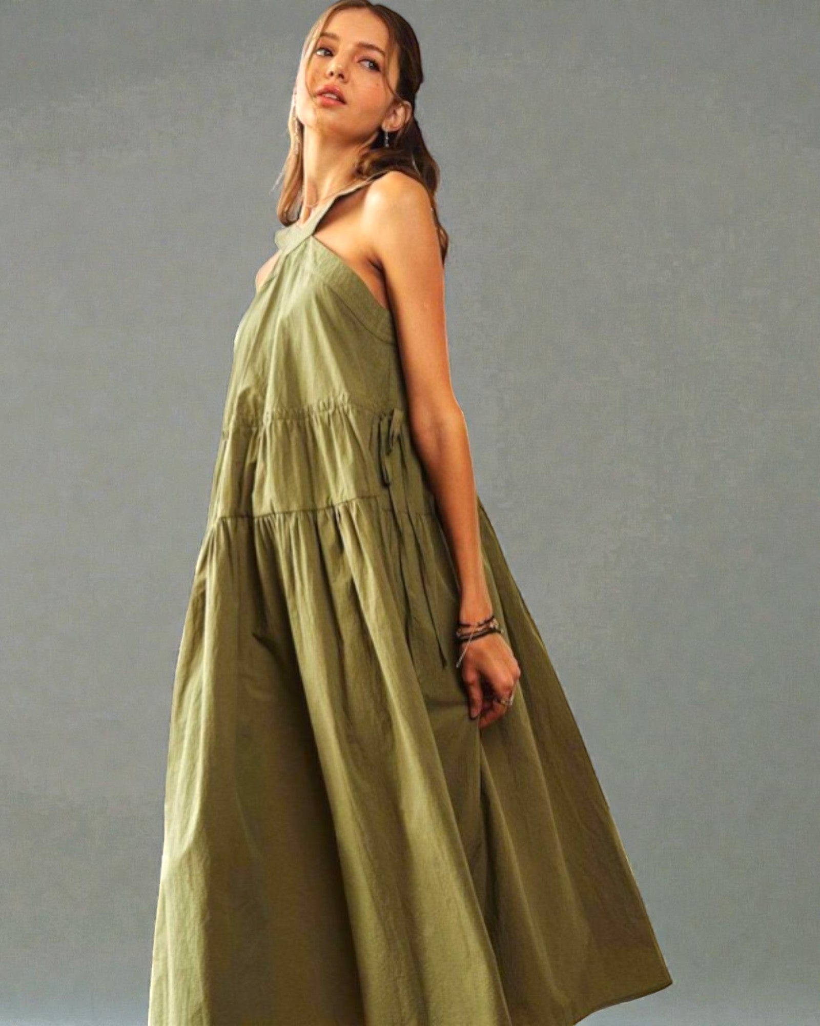 Woman wearing a long green dress against a gray background